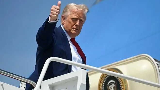 Donald Trump faz sinal de positivo no alto da escada do avião