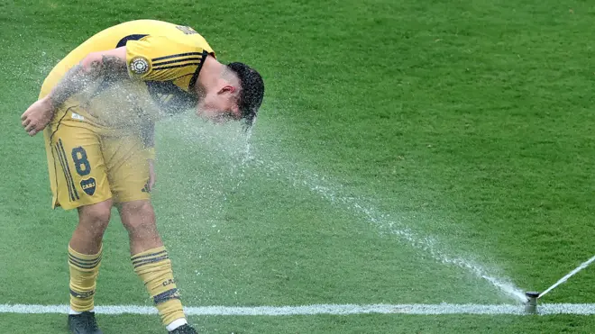كارلوس بالاسيوس لاعب نادي بوكا جونيورز يستفيد من رشاش مياه في أرض الملعب للتبريد خلال مباراة فريقه مع أوكلاند سيتي في مونديال الأندية