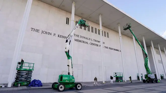 米ワシントンにあるジョン・F・ケネディ舞台芸術センターの白い建物の前に、緑色のクレーン車2台がある。それぞれに作業員が乗っている。地上にも複数の作業員が立っている。建物の外壁には「ドナルド・J・トランプ・アンド・ジョン・F・ケネディ舞台芸術センター」と表記されている
