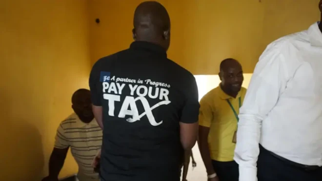 Man wearing t-shirt wey dem write Pay your tax for di back