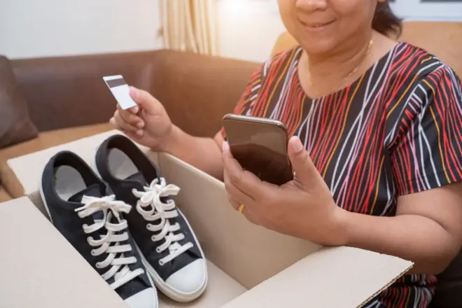 Asian young woman received online shopping parcel opening boxes and buying fashion items by using credit card