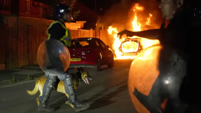 Policial passa com cãojogos de cartas canastra online gratisrua com um carrojogos de cartas canastra online gratischamas ao fundo 