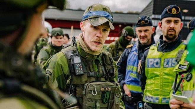 Un soldado sueco con policías. 