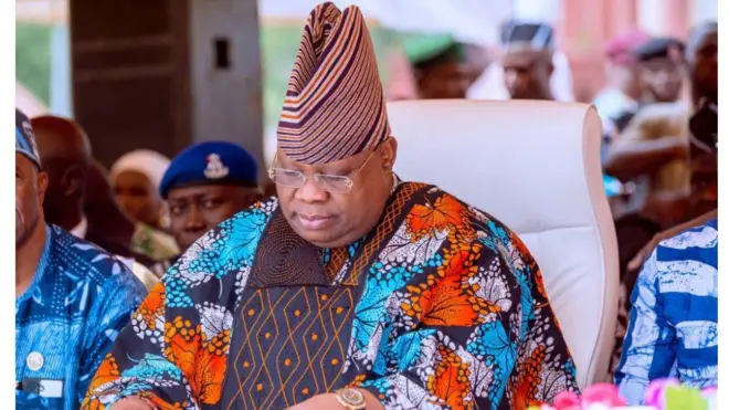 Gomina ipinlẹ Osun, Ademola Adeleke. O wọ agbada ankara, de fila, o si lo igo soju.