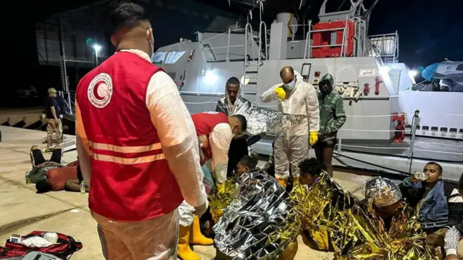 የቀይ ጨረቃ ሠራተኞች ከአደጋው የተረፉ ስደተኞችን ሲያነሱ