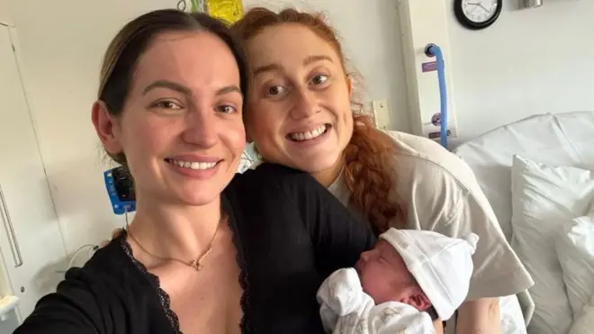 Georgia yeni doğmuş bir bebeği tutarken yanında Daisy yer alıyor. 