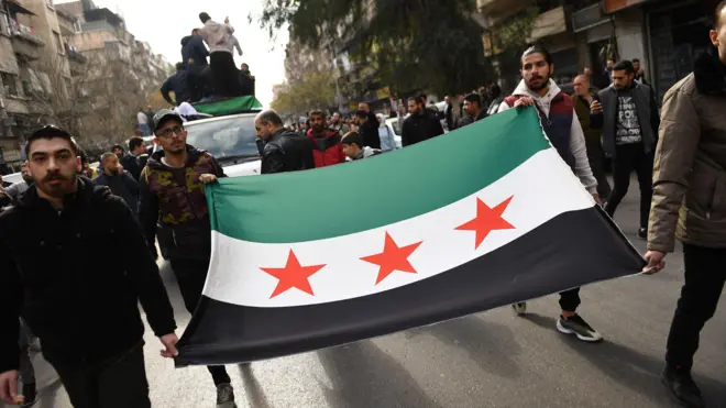 صورة تظهر سوريين يرفعون علم "الثورة السورية في الشارع.