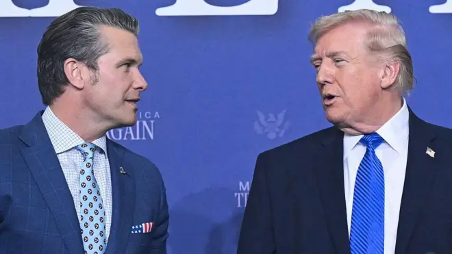 Слева министр обороны США Пит Хегсет, справа президент Дональд Трамп, они сфотографированы в момент обмена репликами. Хегсет выделяется платком в виде американского флага в нагрудном кармане пиджака