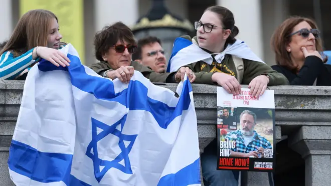 zastava izraela, izraelska zastava, žene drže izraelsku zastavu na protestu u Londonu
