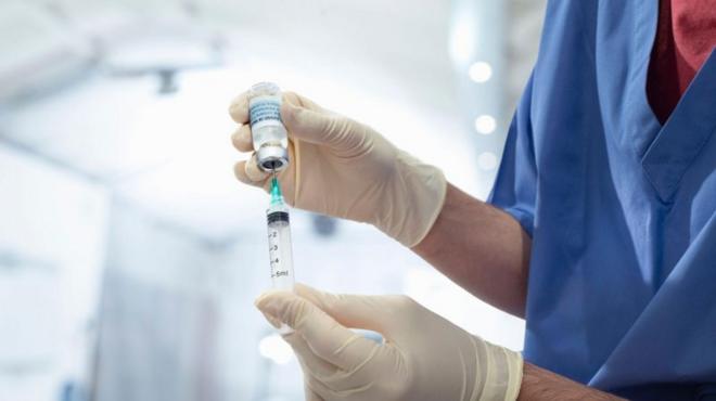 Pessoa manipulando seringa com vacina da dengue