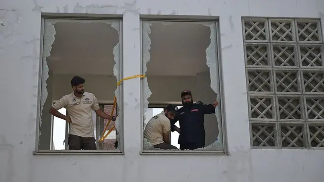 Police look on from shattered windows at the scene following a fire outside the Mother and Child Health (MCH) ward at the Pakistan Institute of Medical Sciences (PIMS) Hospital in Islamabad on August 26, 2026. A fire in a maternity ward at a public hospital in the Pakistani capital Islamabad on August 26 morning killed 14 children, a local authority said.