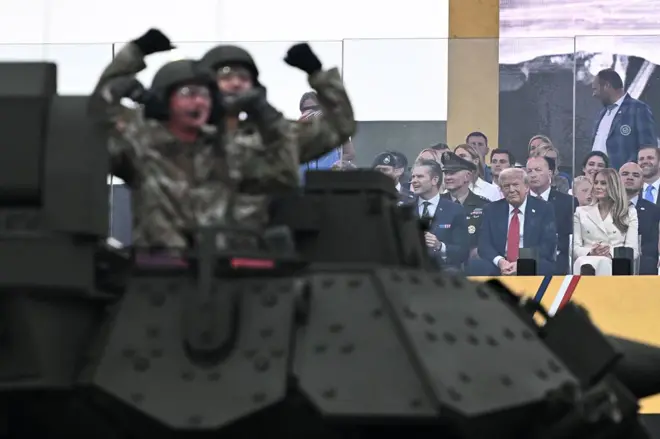 Soldados en un tanque en Estados Unidos saludan a la multitud mientras observa el presidente Donald Trump