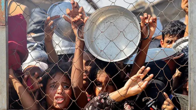 22 Temmuz 2025 tarihinde Gazze Şeridi'nin güneyindeki Han Yunus'ta Mavasi bölgesinde bir yardım kuruluşunun dağıttığı yemeği almak için bekleyen çocuklar