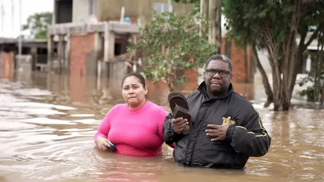 Rosana e Nelson com água até a cintura e roupasavião betanofrioavião betanouma rua alagada