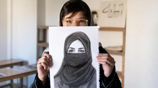 الفتاة مهدية تمسك بصورة من رسمها