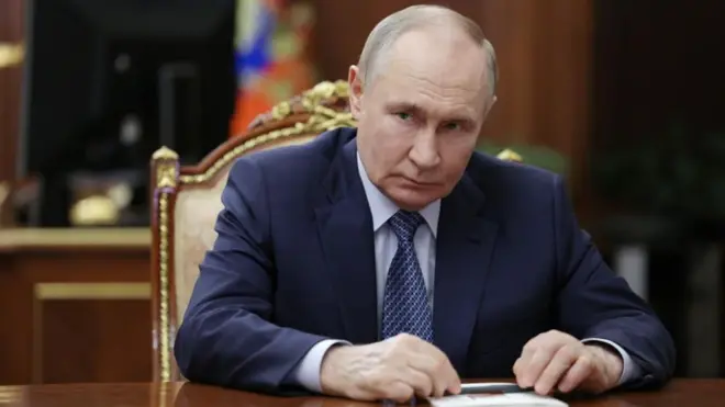 Russian President Vladimir Putin, sat down at a desk with a pen and paper in front of him