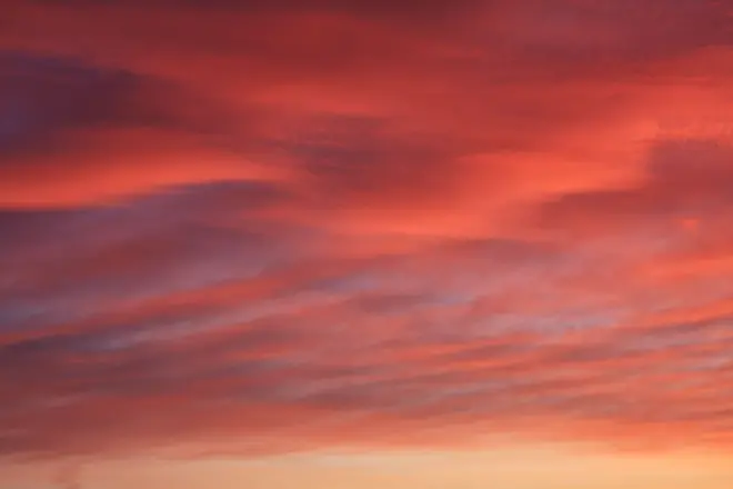 آسمان ابری که در غروب سرخ رنگ شده است