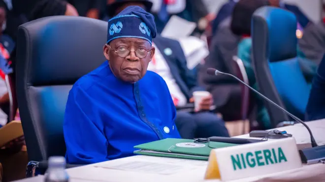 Tinubu wearing blue dress wit glass