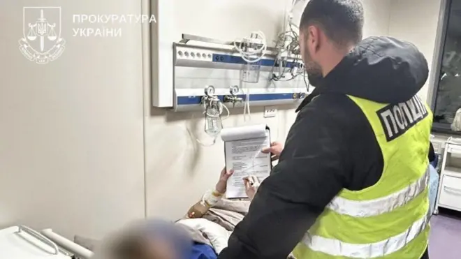 Поліцейський надає документ на підпис підозрюваному, який лежить на ліжку