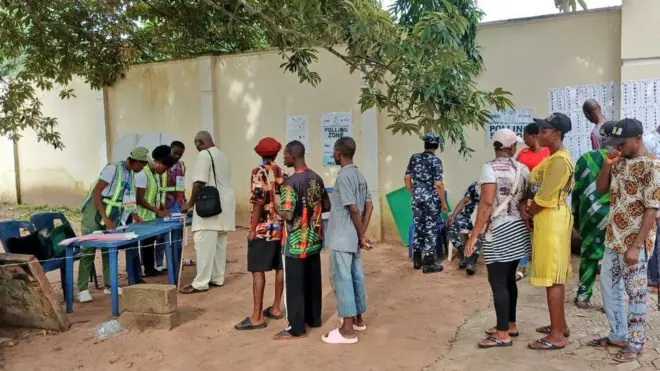 Voters stand for line to vote as two Inec ad-hoc staff dey ready wit dia materials
