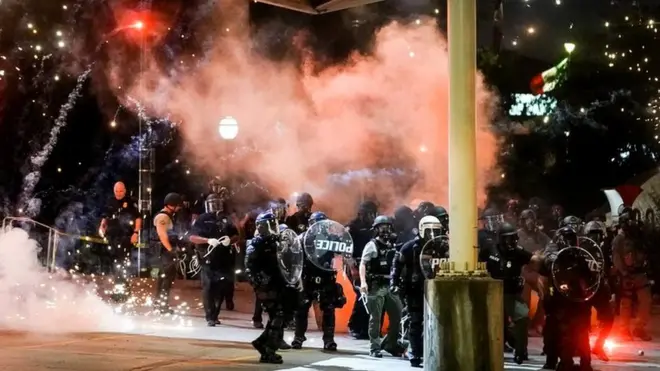 A firework explodes near a police line during a protest in Atlanta, Georgia