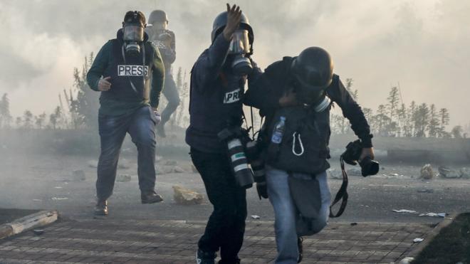 Journalists with tear gas masks at protest in West Bank
