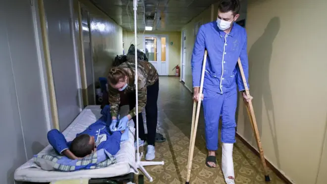 Двое мужчин в больничной одежде - один на костылях, другой на койке