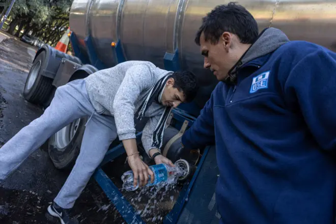 Un hombre rellena una botella de plástico de un camión con agua potable en Montevideo.