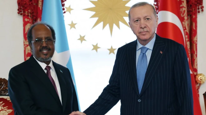 Cumhurbaşkanı Recep Tayyip Erdoğan ve Somali Cumhurbaşkanı Hasan Şeyh Mahmud el sıkışıyor. Somalili gülüyor, Erdoğan net bakıyor.