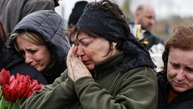 People mourn at the cemetery in Bucha