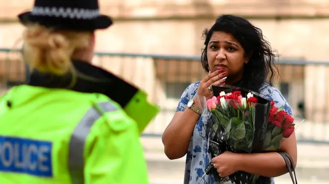 Жінка, яка принесла квіти до місця трагедії, розмовляє з поліцією