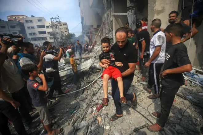 इसराइली हमले में तबाह हुई गज़ा की एक इमारत से घायलों को निकाला जा रहा है