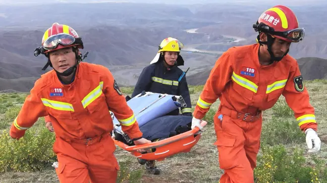 This photo taken on May 22, 2021 shows rescuers carrying equipment as they search for runners who were competing in a 100-kilometre cross-country mountain race when extreme weather hit the area, leaving at least 20 dead, near the city of Baiyin in China's northwestern Gansu province