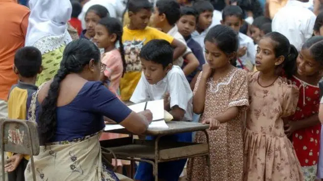 A Sri Lankan school teacher registers school children at the Sudarma Ram school in the southwestern coastal town of Magalle 10 January 2005