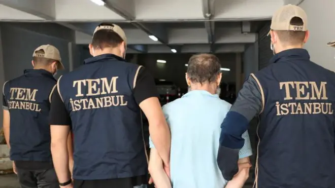 Yeleklerinin arkasında TEM istanbul yazılı ekip üyelerinin üçünde de şapka var. İkisi solda biri sağda duruyor aralarında mavi tişörtlü bir erkek var, hepsinin arkası dönük. 