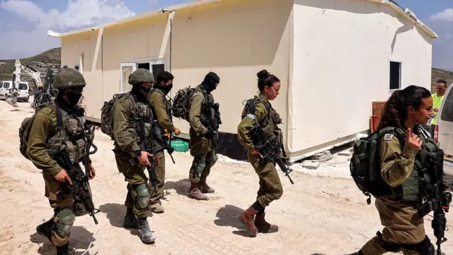 Israeli soldiers patrol outside the construction of a portable building at the Homesh site in the West Bank on 29 May 2023.
