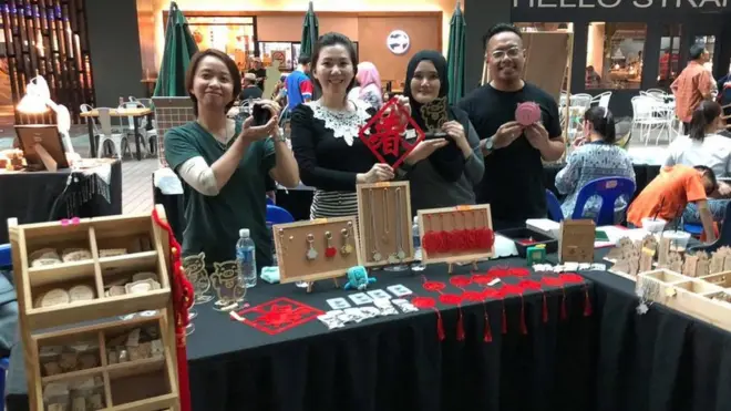 Yuslina Badrum (dua dari kiri) dan suaminya, Adam Baderum, menjual pernak-pernik babi di Sabah jelang tahun baru Imlek.