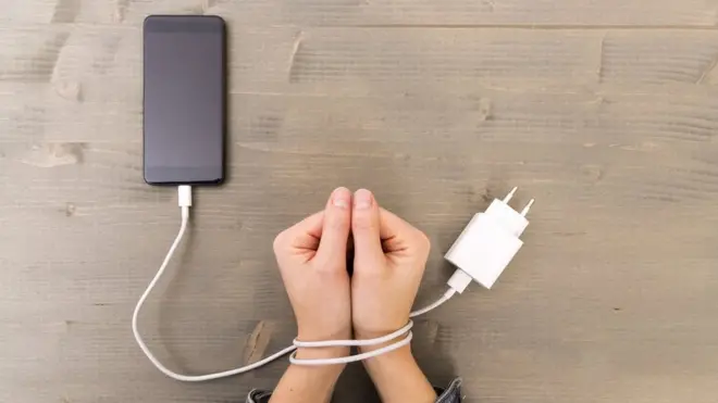 Photo d'une main attachée à un câble téléphonique.