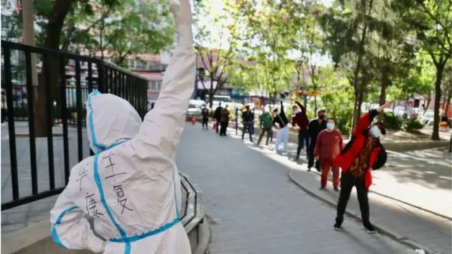 مواطنون صينيون من سكان بكين يمارسون تمارين رياضية أثناء انتظارهم في الطابور لإجراء فحص الحمض النووي.