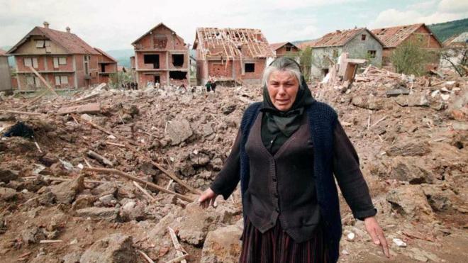 An elderly woman cries as she stands next to the rubble of destroyed houses, 28 April 1999 in Surdulica