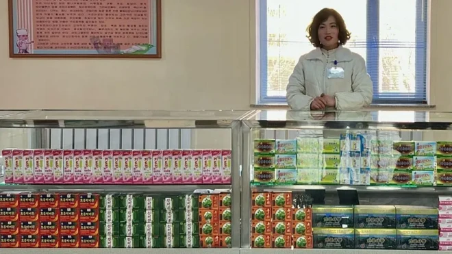 یک زن پشت پیشخوان با کالاهایی که در ویترین دیده میشوند