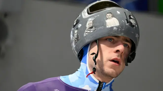 Владислав Гераскевич носи кацигу са сликама погинулих у рату у Украјини на стази за скелетон у Кортини, у Италији, на Зимским олимпијским играма