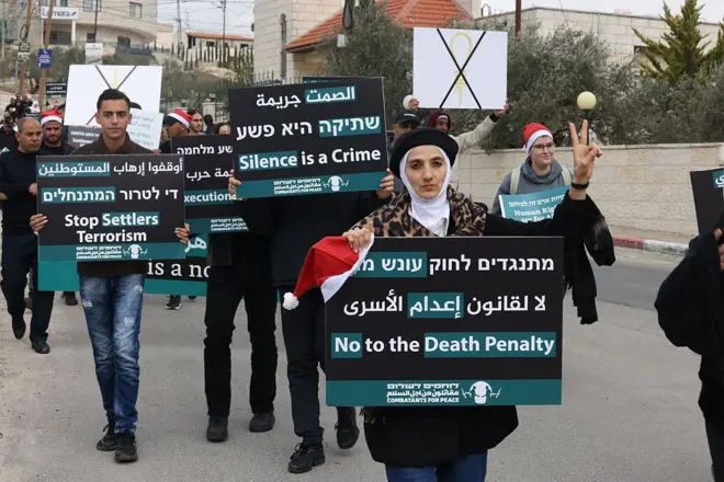 Палестинские и израильские активисты собрались на акции протеста в декабре против тогдашнего проекта закона, который предусматривал смертную казнь для палестинцев, осужденных за убийство израильских граждан, недалеко от Бейт-Джалы на оккупированном Израилем Западном берегу.