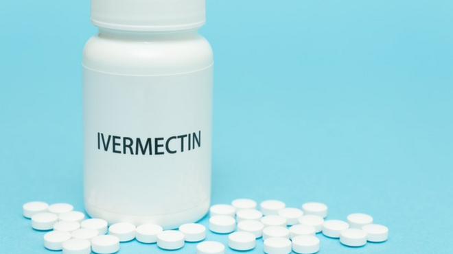 Frasco de ivermectina com comprimidos brancos ao redor