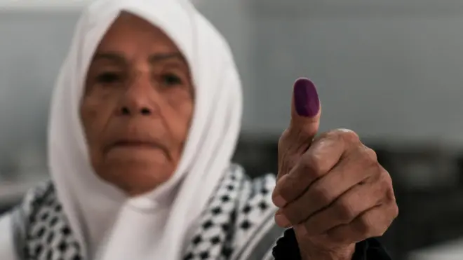 امرأة فلسطينية تُظهر إصبعها الذي يحمل علامة بعد الإدلاء بصوتها في مركز اقتراع خلال الانتخابات البلدية في مدينة الخليل في الضفة الغربية المحتلة في 25 أبريل/نيسان 2026.