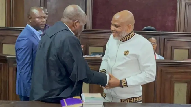 Nnamdi Kanu shaking hands with a lawyer