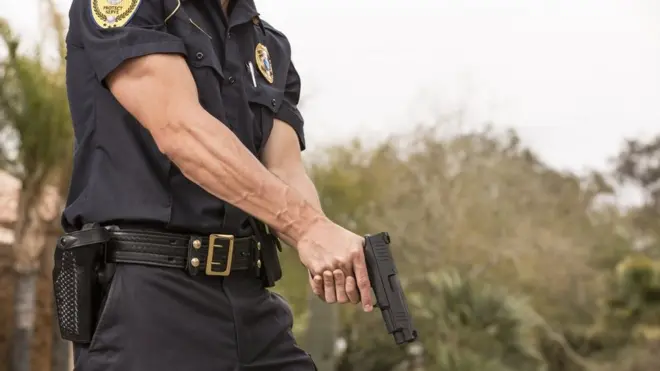 Policía sostiene una pistola.