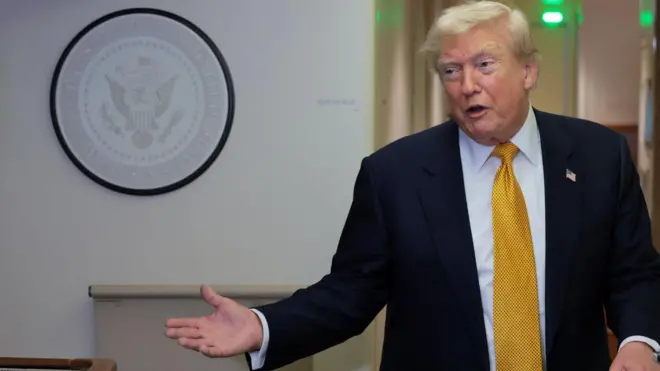 Доналд Трамп у тамном оделу са жутом краватом