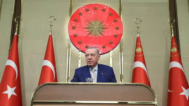 Cumhurbaşkanı Erdoğan bayraklar ve cumhurbaşkanlığı forsunun arasında kürsüde konuşma yapıyor