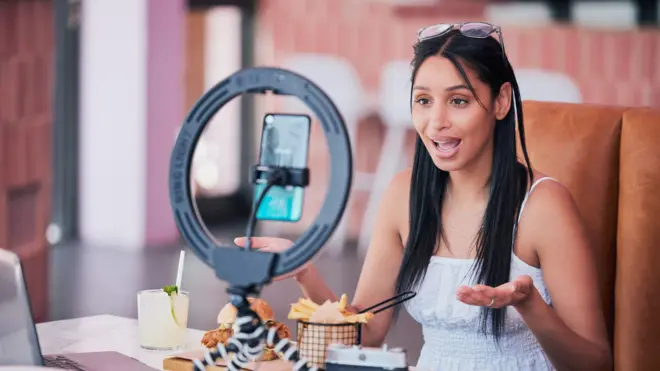 Woman influencer, food review blog and content creator filming online video in cafe restaurant. Creative live streaming, shooting 5g web vlog and virtual mobile phone app broadcast for social media